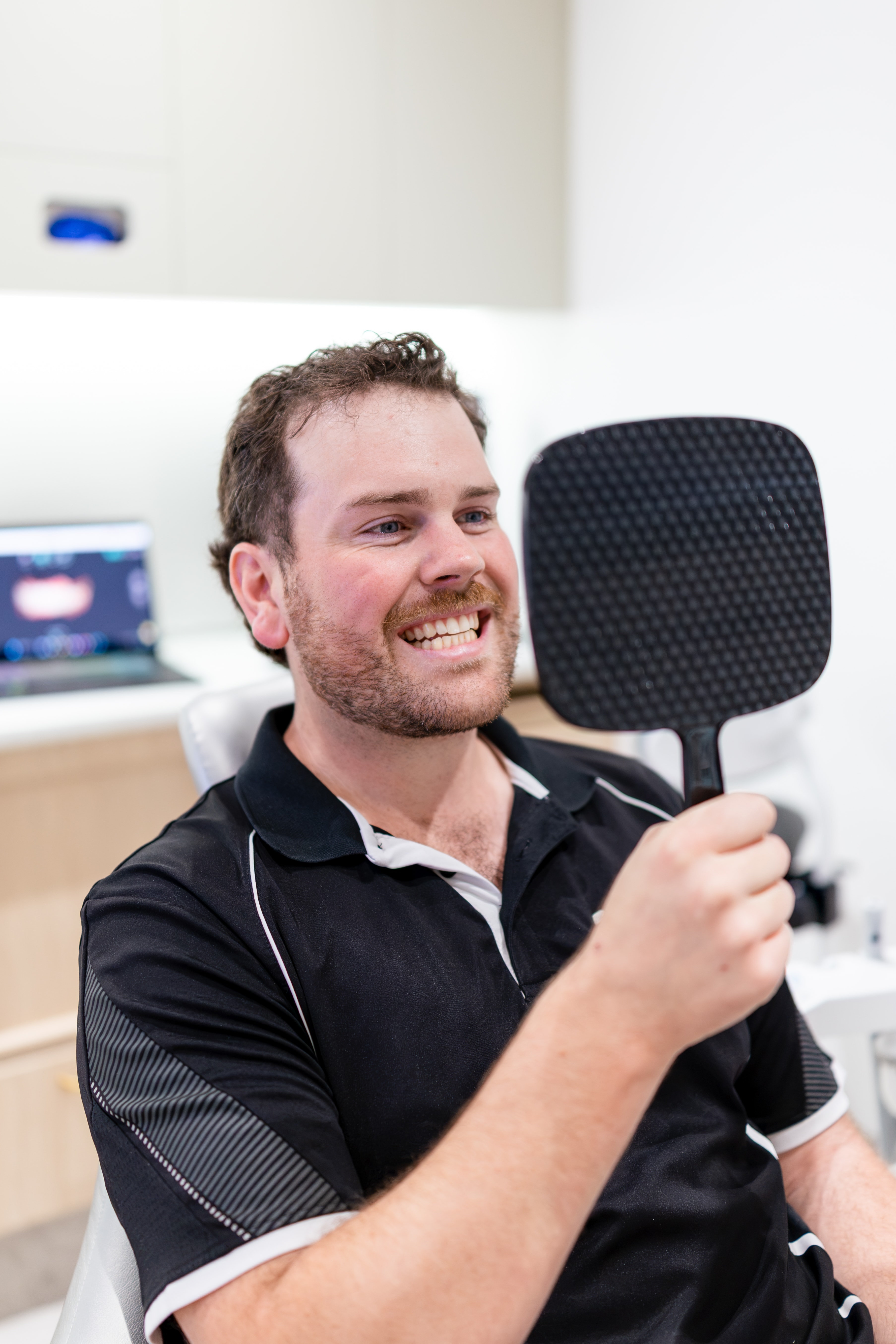 Patient reviewing cosmetic smile goals in a handheld mirror