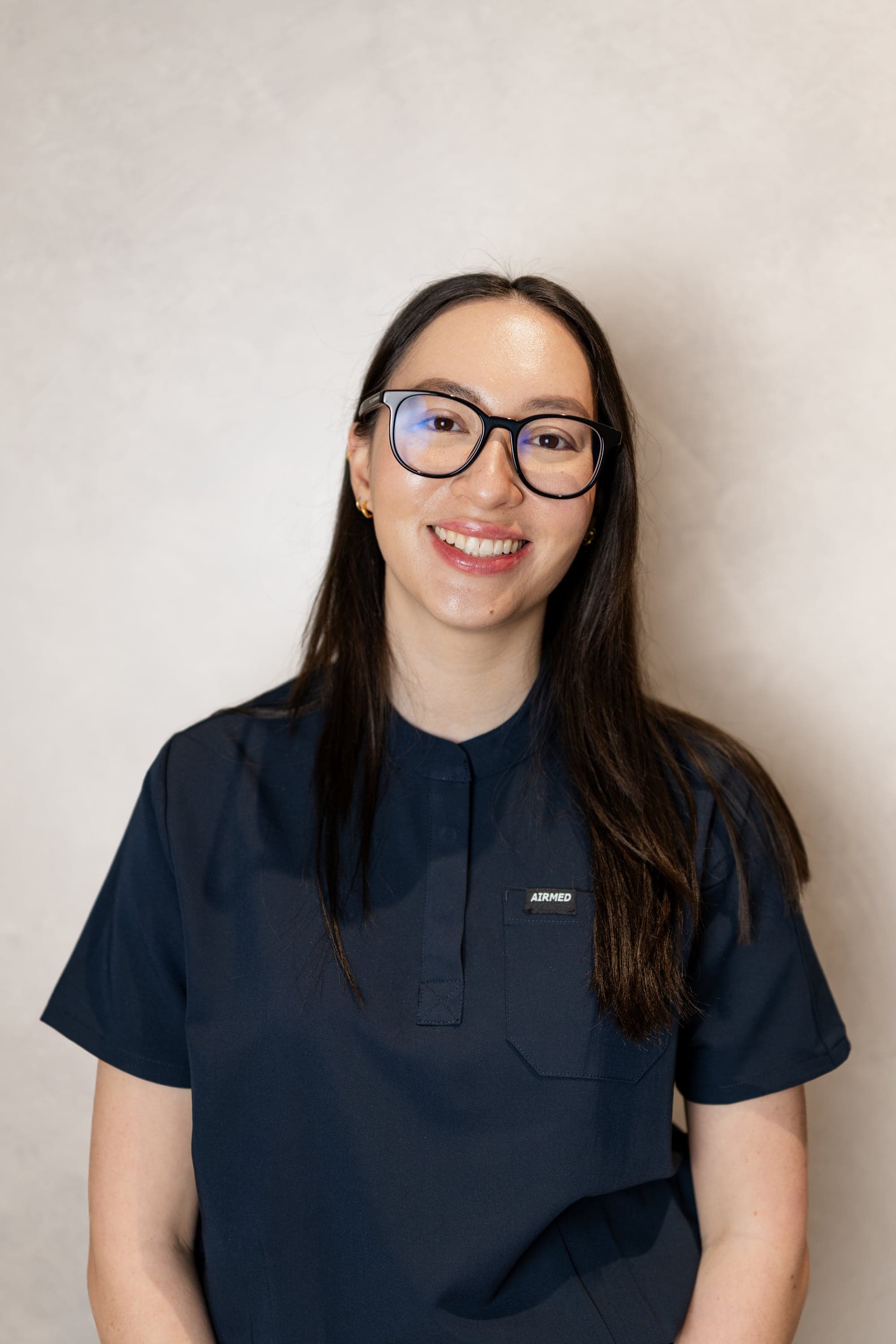 Dr Cassandra Thea Peters, Associate Dentist at Joyner Family Dental, smiling in black scrubs